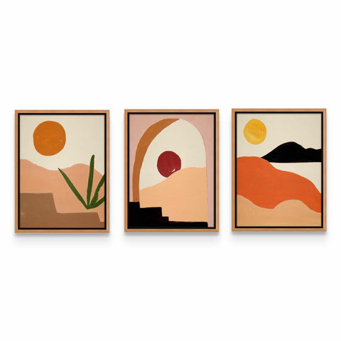 three framed paintings of desert scenes on a white wall