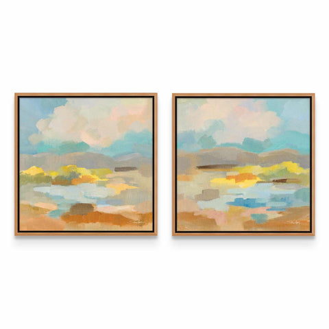 two paintings of water and clouds hanging on a wall
