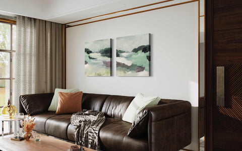 a living room with a brown couch and two paintings on the wall