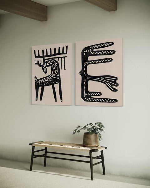 two black and white paintings on a wall above a bench