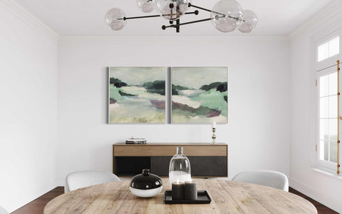 a dining room table with two paintings on the wall