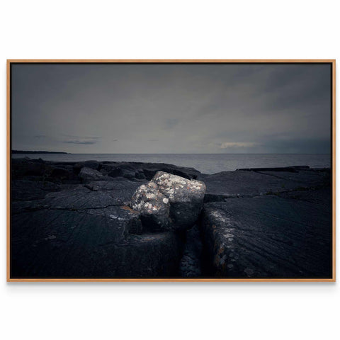 a black and white photo of a rock in the water