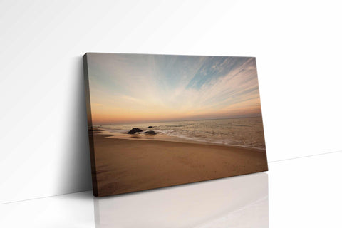 a picture of a beach at sunset with a rock in the foreground