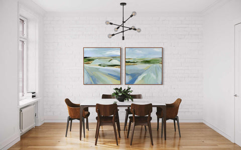 a dining room with two paintings hanging on the wall