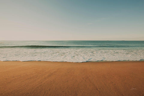 a sandy beach with waves coming in to shore