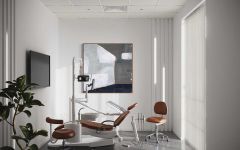 a dentist's chair in a white room with a painting on the wall