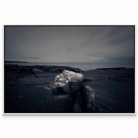 a black and white photo of a rock in the water