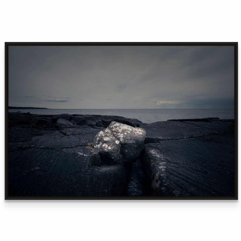 a black and white photo of a rock in the water