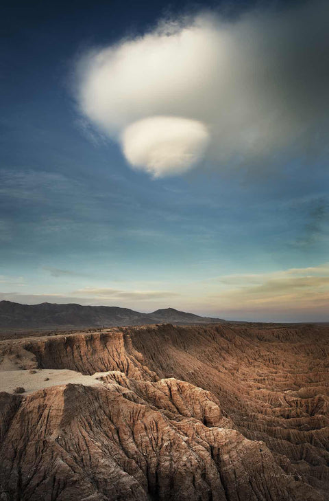 a large cloud is in the sky over a desert