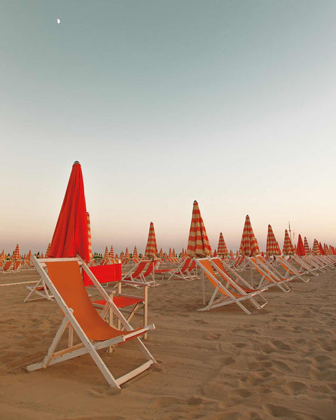a row of beach chairs sitting on top of a sandy beach