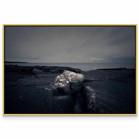 a black and white photo of a rock in the water