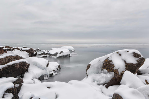 a body of water surrounded by snow covered rocks