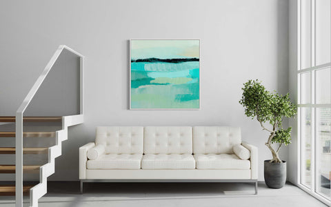 a living room with a white couch and a painting on the wall