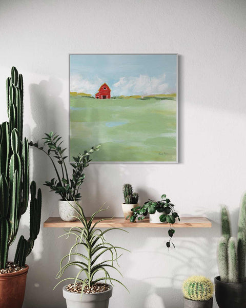 a painting of a red house on a shelf next to cacti