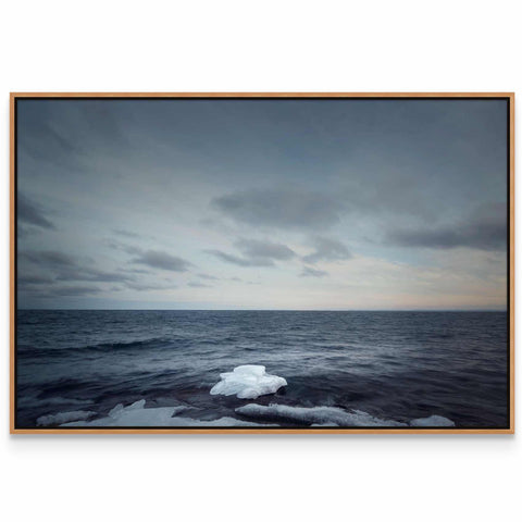 an iceberg floating in the ocean on a cloudy day