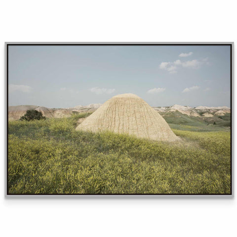 a large mound of sand in a grassy field