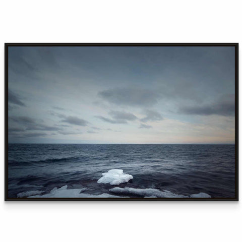 an iceberg floating in the ocean under a cloudy sky